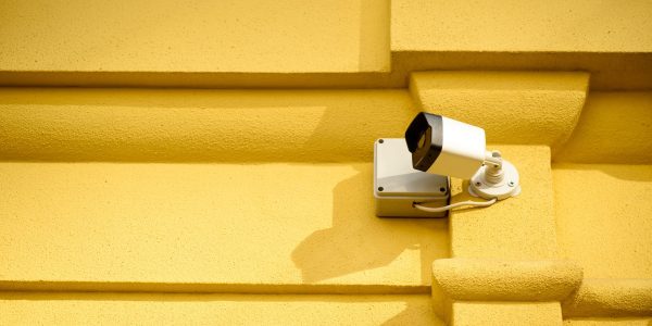 close up view of security camera on yellow building facade
