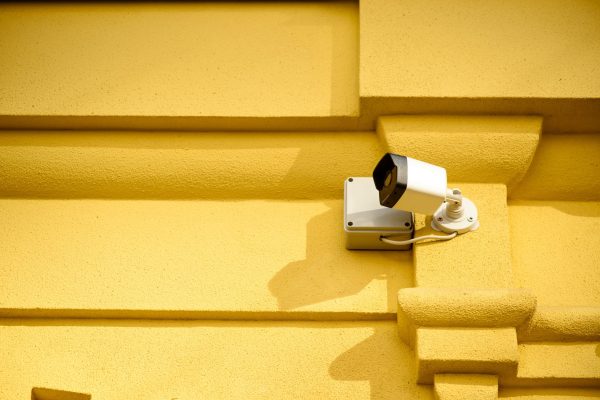 close up view of security camera on yellow building facade