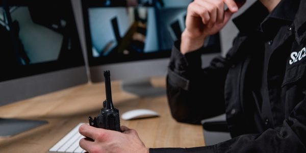cropped view of guard in uniform holding walkie-talkie