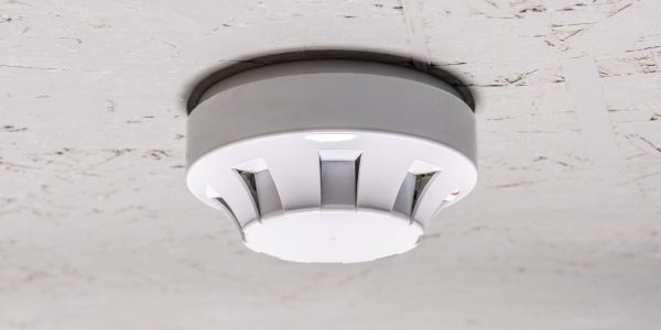 smoke detector of fire alarm on white ceiling at home