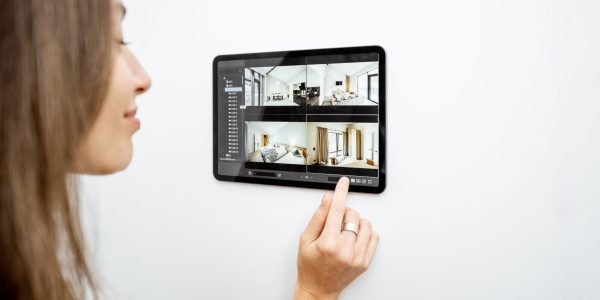 Young woman watching video from security cameras on a digital tablet at home. Concept of remote video surveillance over the internet with smart devices